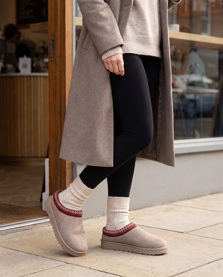 Apricot suede-look slippers with black leggings, cream socks and a taupe coat outside a café